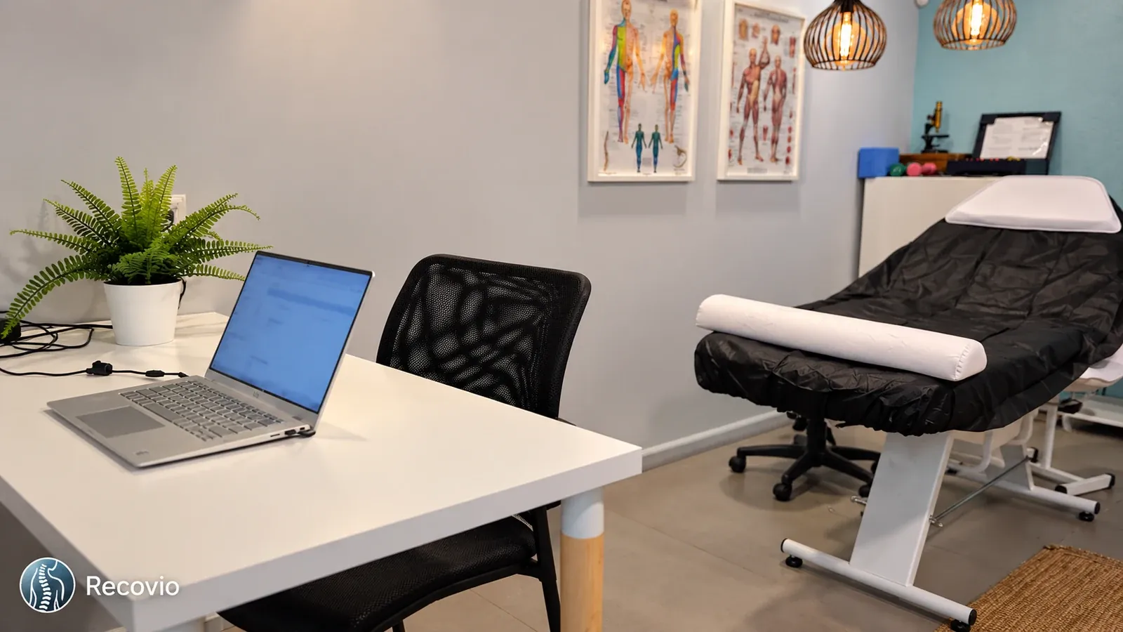Bureau de consultation, ordinateur et chaise près d'une table de soins chez Recovio, d'après une photographie fournie